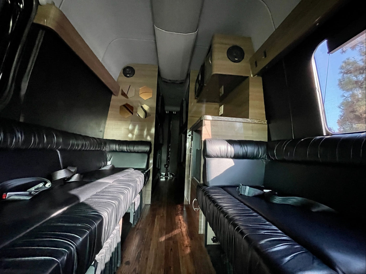 Luxury RV rental interior with black leather seating, wood flooring, and custom cabinetry for comfortable travel.