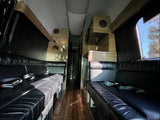 Luxury RV rental interior with black leather seating, wood flooring, and custom cabinetry for comfortable travel.