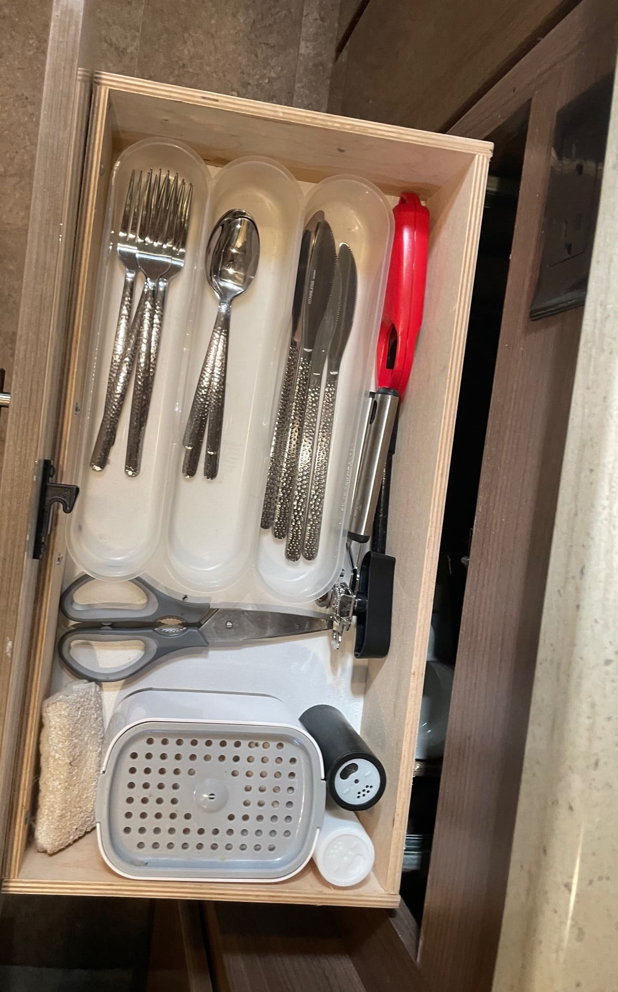 Kitchen drawer in an RV rental with organized cutlery, a lighter, and kitchen shears in compact storage.