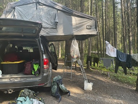  featuring a vehicle with a roof-top tent.|Forest camp with SUV rooftop tent setup & drying clothes. Great alternative to an RV rental for nature travel.|A grey SUV with a rooftop tent — photo 8