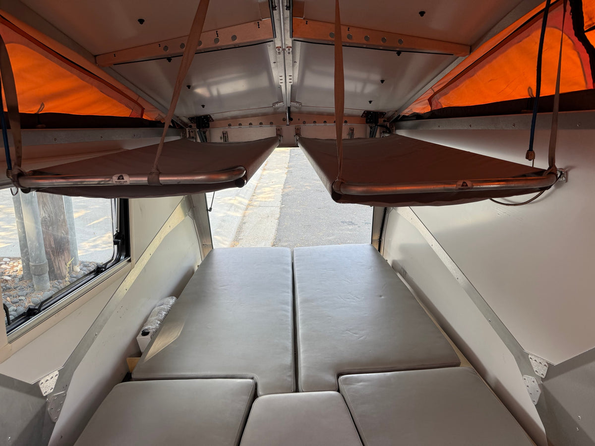 RV rental interior: pop-top camper with modular bed/seating and two suspended bunks. Spacious & versatile. — photo 8