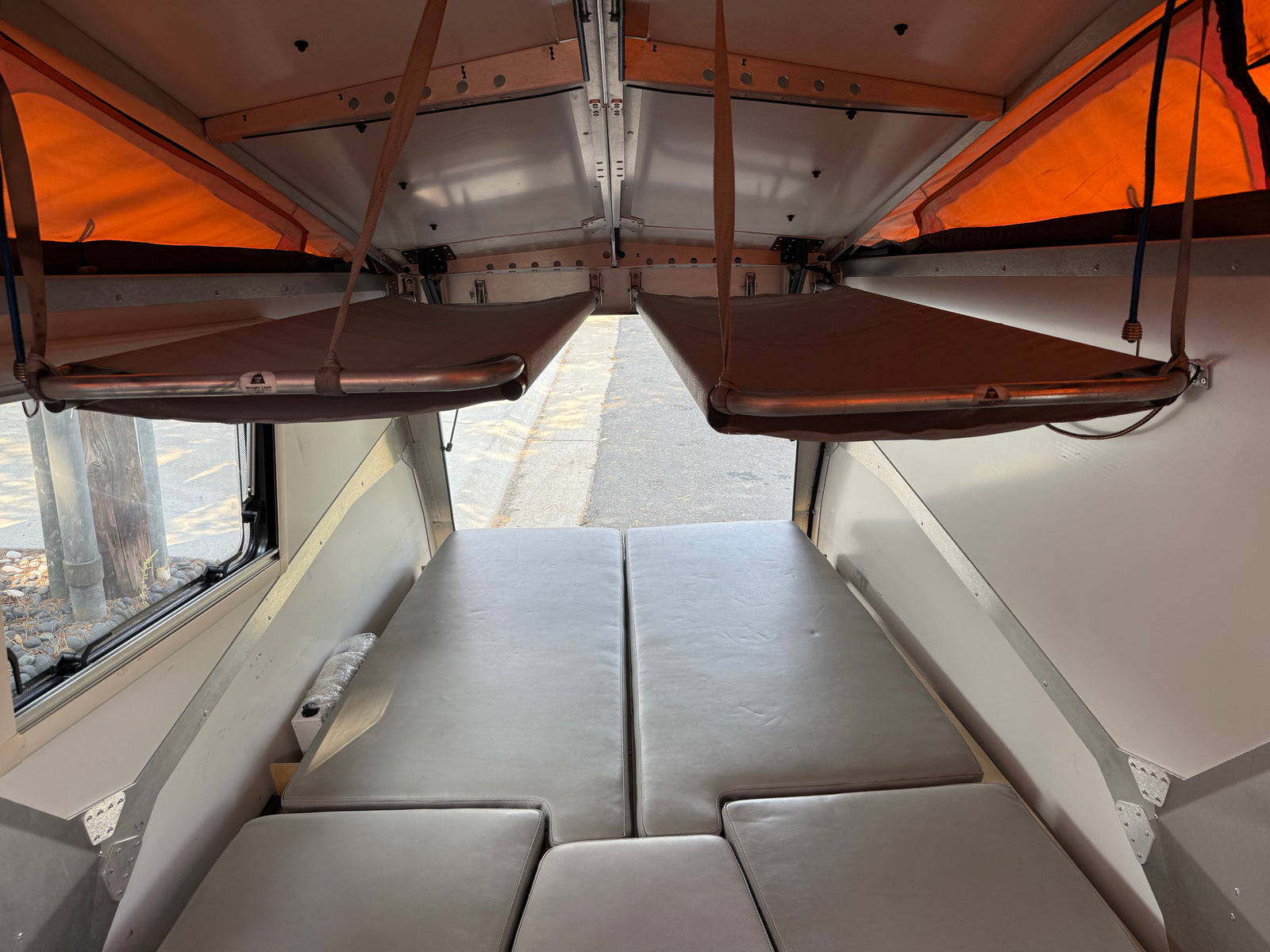 RV rental interior: pop-top camper with modular bed/seating and two suspended bunks. Spacious & versatile.