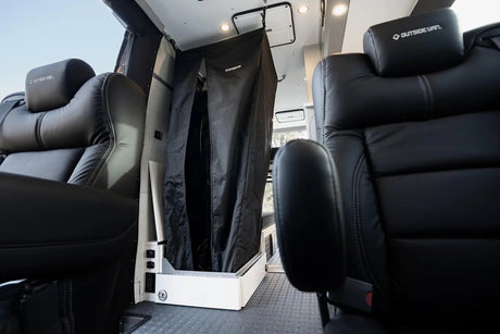 RV rental interior: luxurious black seats flank a versatile black curtained enclosure, possibly a shower/storage unit.