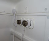 RV rental shower interior: white, compact, featuring a handheld sprayer and dual faucet controls.