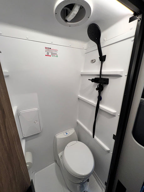 Experience comfort in a compact RV rental wet bath, complete with a toilet, shower, and ceiling vent for travel.