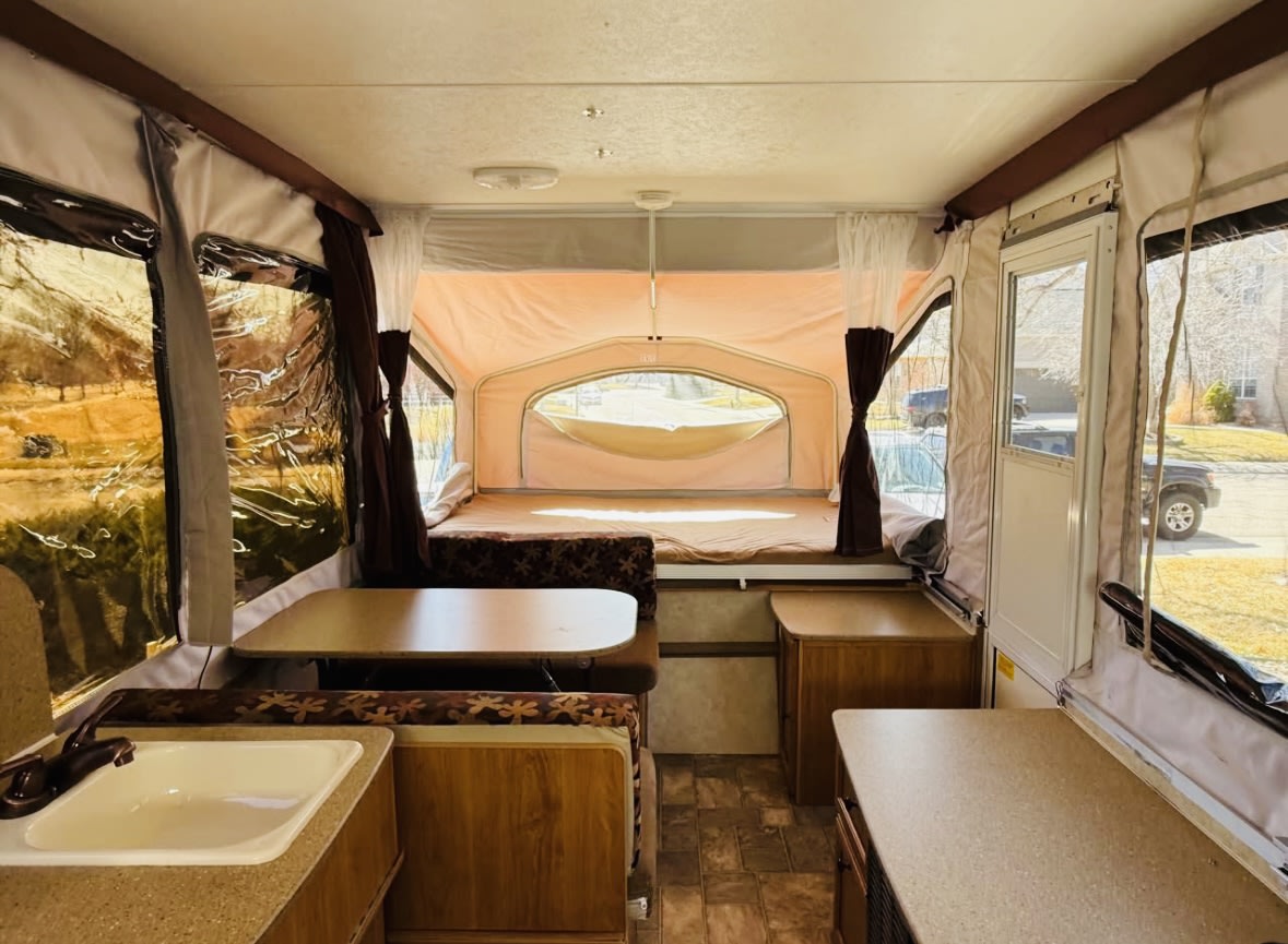Spacious pop-up camper interior, perfect for your next rv rental, featuring beds, dining area, and a kitchen sink. — photo 4