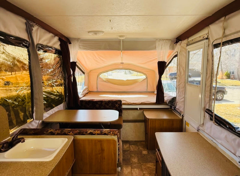 Spacious pop-up camper interior, perfect for your next rv rental, featuring beds, dining area, and a kitchen sink. — photo 4