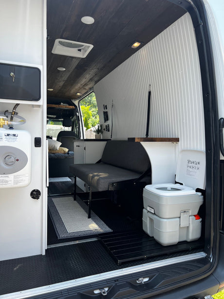 Inside this RV rental camper van: full amenities with a kitchenette, flexible seating, portable toilet, and water heater.
