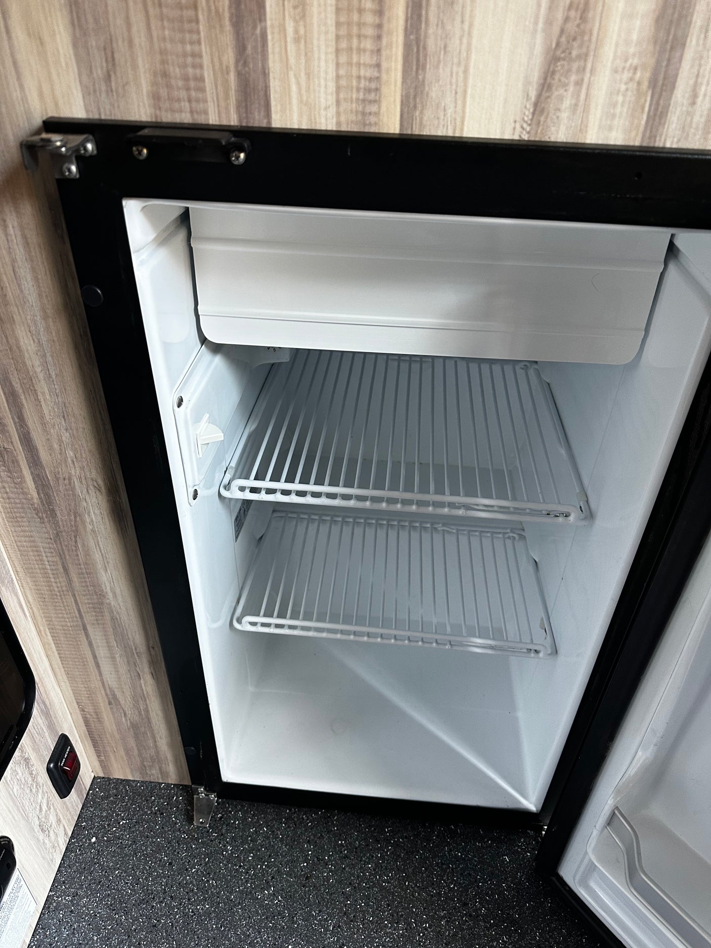 Inside an rv rental: A compact, open mini-fridge with two shelves and a small freezer compartment, ready for your road trip.