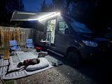 Nighttime rv rental with dogs relaxing on an illuminated outdoor setup. A cozy campervan experience with furry friends.