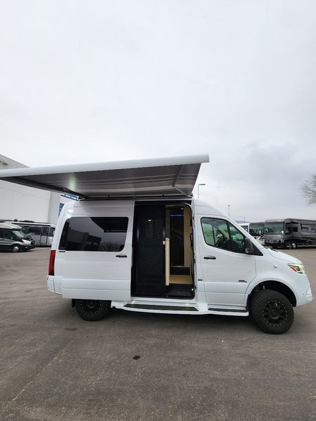 White off-road camper van with extended awning & open door. Your next rv rental adventure awaits!