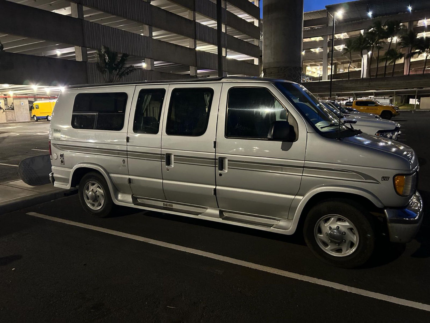 Night shot of a silver Ford RV rental van in a parking garage. Ideal for travel and adventure.