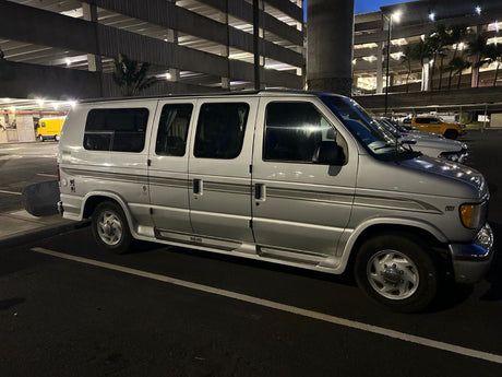 Night shot of a silver Ford RV rental van in a parking garage. Ideal for travel and adventure.