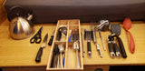 RV rental kitchen essentials: kettle, knives, cooking utensils, measuring cups, and tools arranged on a counter.
