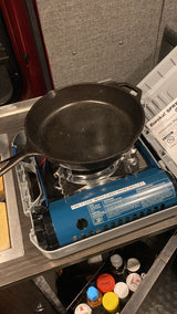 Cast iron skillet on a Eureka! SPRK portable camp stove inside an RV rental. Ideal for cooking during van life.