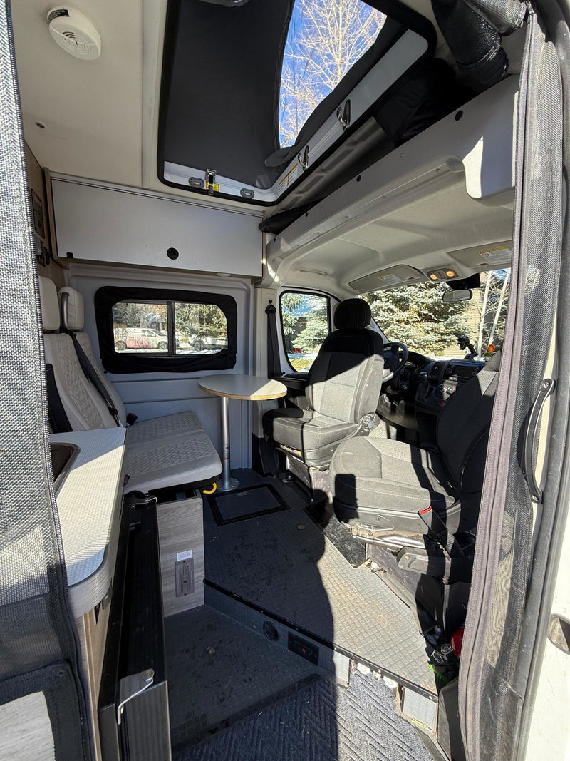 RV rental: Camper van interior with open pop-top roof, dining table, small kitchen, and front cab area. — photo 13