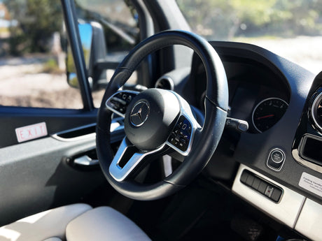 View inside a modern Mercedes-Benz RV rental: the steering wheel with integrated controls, sleek dashboard, and push-button start.