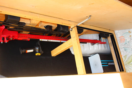 RV rental under-bed storage with a Hi-Lift jack, car jack, water tank, and Renogy power unit.