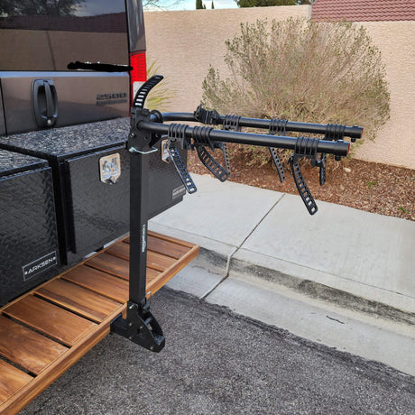 Tail of an RV rental van equipped with a multi-bike rack, ARKSEN storage boxes, and a wooden rear deck.