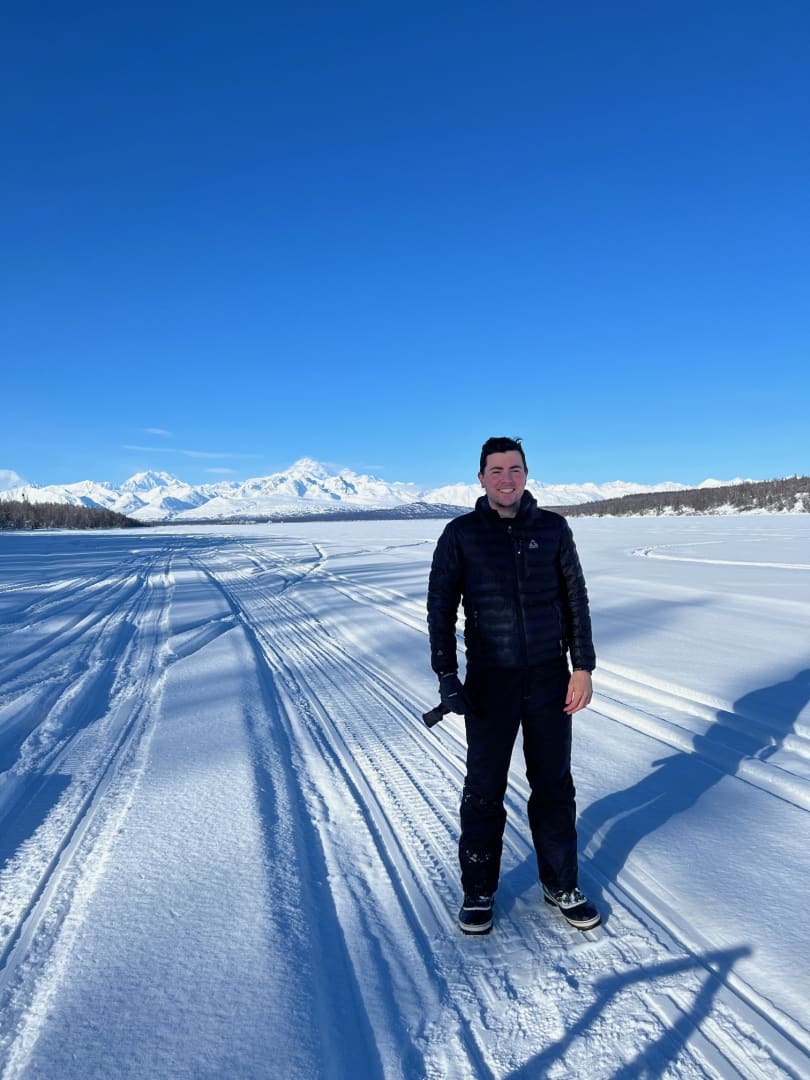 Enjoying the vast winter landscape: a man stands on a snowy path with distant mountains, ideal for an RV rental trip.
