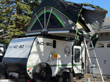NO BO RV rental: A white No Boundaries camper with an open rooftop tent & ladder for your next outdoor adventure.