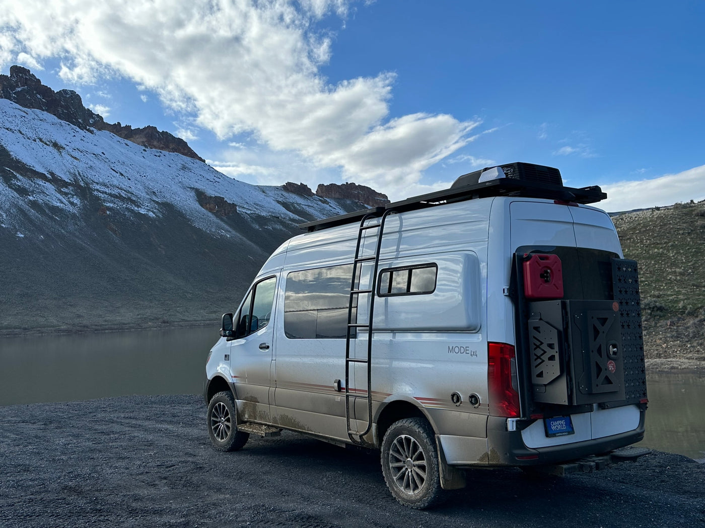  a woman & dog enjoy a serene lake view amidst forested mountains. Ideal for nature escapades.|Adventure seekers atop their RV rental van — photo 17