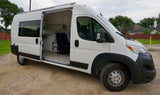 White van RV rental with open side door revealing a converted camper van interior with a bed and seat.