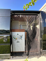 Open side of an RV rental showing its custom interior with kitchen and US travel map. A mesh screen covers the doorway.