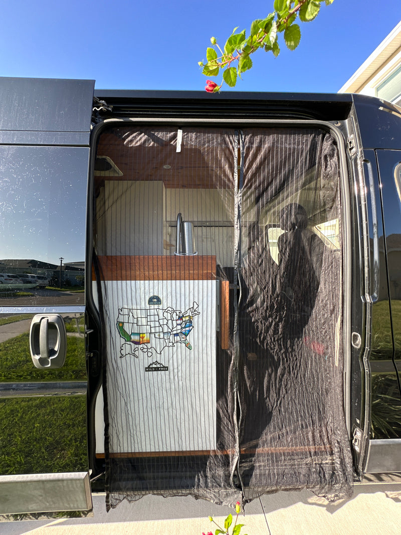 Open side of an RV rental showing its custom interior with kitchen and US travel map. A mesh screen covers the doorway. — photo 14