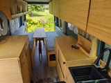 Cozy bamboo interior of an RV rental, featuring a dinette, kitchenette, and ample storage, ideal for travel.