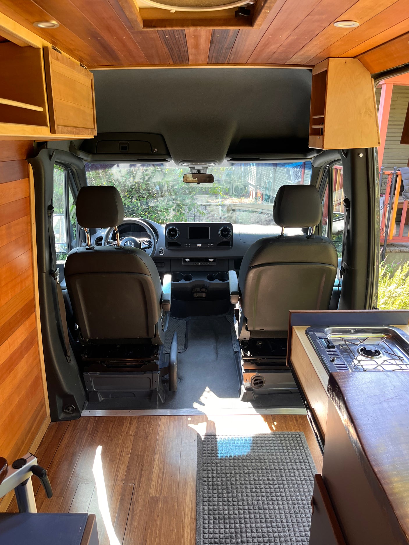 Inside an RV rental: a stylish campervan with wood paneling, compact kitchen, and front cabin area.