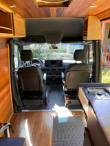Inside an RV rental: a stylish campervan with wood paneling, compact kitchen, and front cabin area.