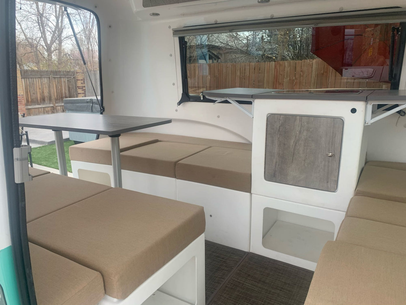 Cozy RV rental interior showing modular bench seats, convertible tables, and a compact kitchen unit for travel.