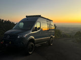  ready for exploration.|Adventure-ready Mercedes Sprinter RV rental at a scenic sunset vista. Perfect for van life exploration.|Adventure-ready RV rental: A rugged Storyteller Overland Sprinter van with off-road tires