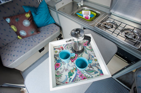 This RV rental offers comfort: a campervan kitchenette with a sink, stove, bench seating, and a coffee setup.