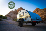 This compact teardrop RV rental is ready for adventure amidst rocky desert landscapes, ideal for camping.