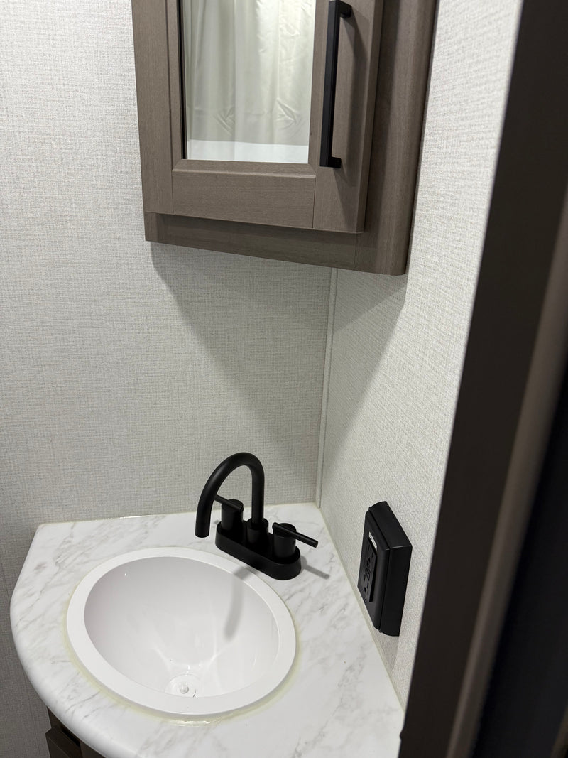 Modern RV rental bathroom sink area: black faucet, white basin, marbled counter, and mirrored medicine cabinet. — photo 3
