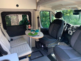 Cozy RV rental interior: dining table set for two, plush seating, and driver's cabin. Ideal for road trips.