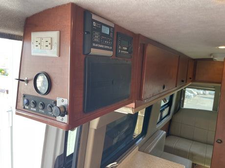 RV rental interior: wood overhead console with solar, power outlets, switches, and storage compartments.