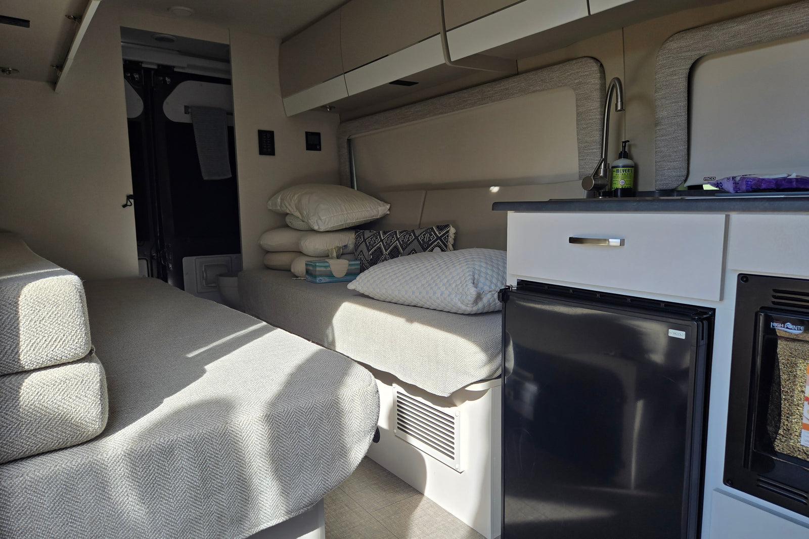 Inside a modern rv rental: twin beds, compact kitchen with sink & fridge. A cozy, functional living space.