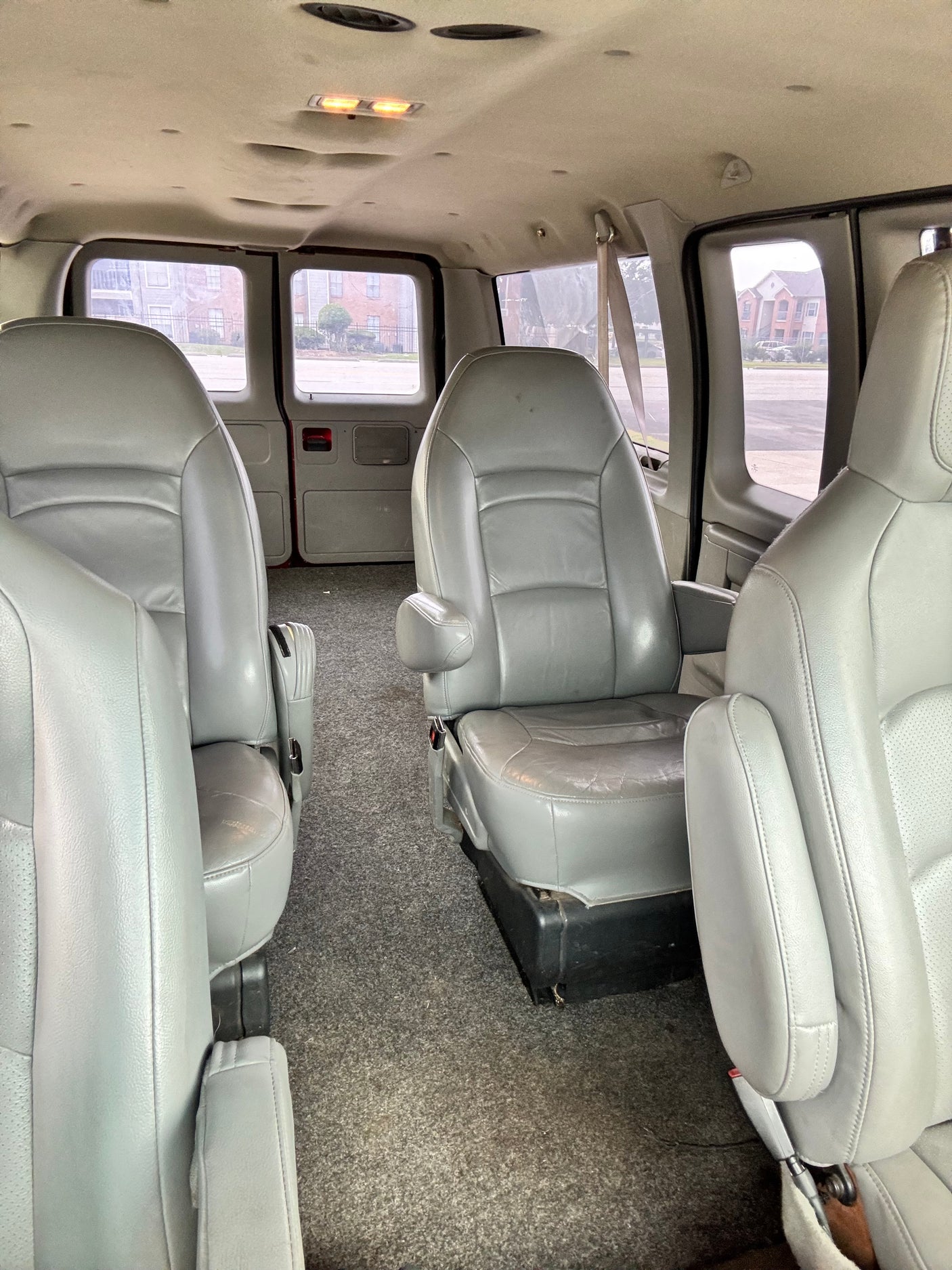 Spacious grey passenger seating and carpeted interior of an RV rental van, with clear windows. Ideal for travel.
