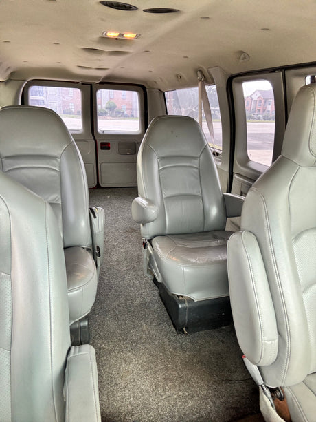Spacious grey passenger seating and carpeted interior of an RV rental van, with clear windows. Ideal for travel.
