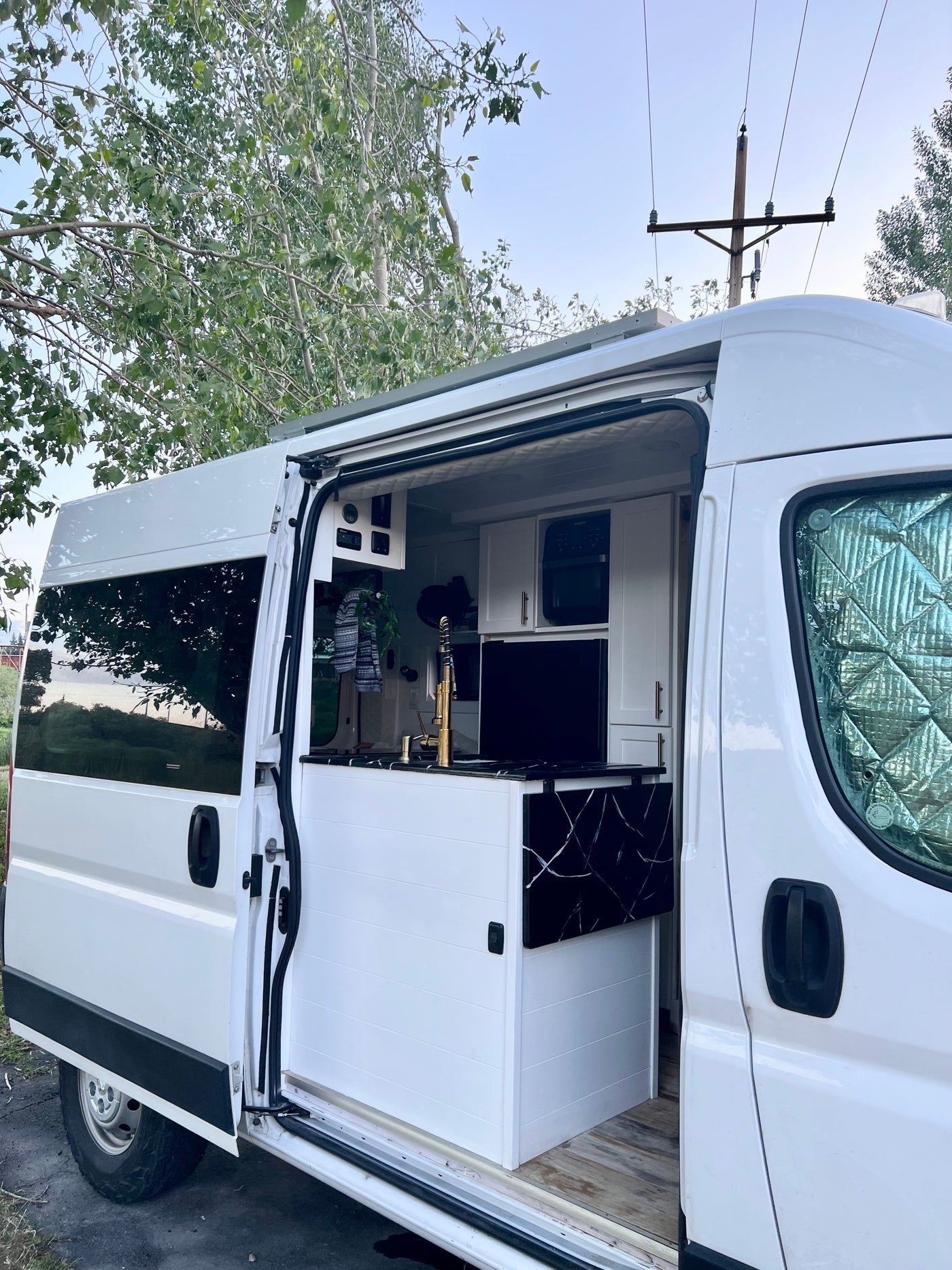 White camper van RV rental. Its open sliding door reveals a sleek interior with a gold-faucet kitchen. — photo 16