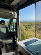 Coastal bliss from an rv rental: passenger seat, kitchen, and ocean views through a mesh screen.