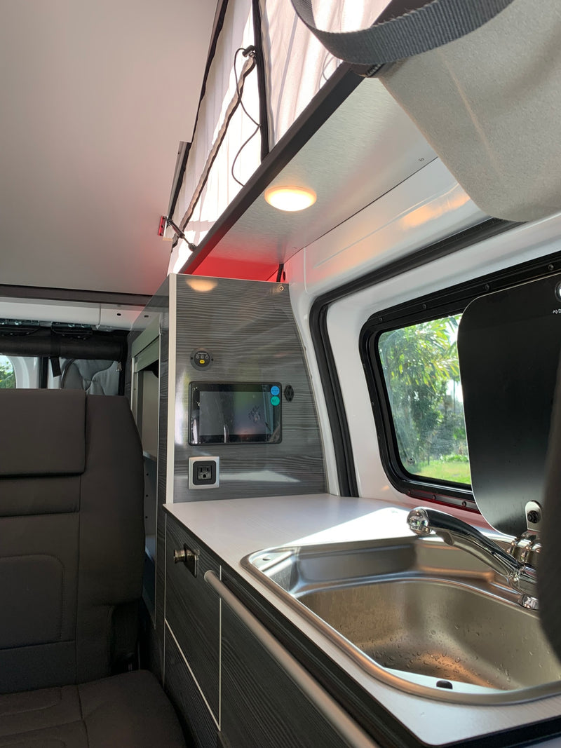  and a raised pop-top roof for travel.|Compact **RV rental** interior: a sleek kitchen features a stainless sink with Dometic cover — photo 18