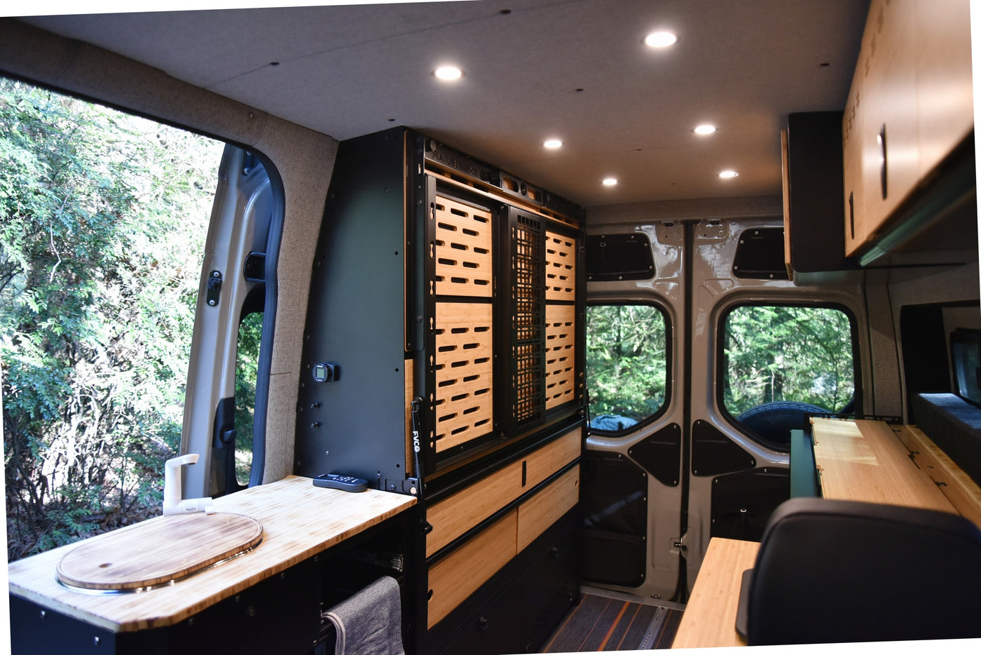 Modern RV rental interior: custom van conversion featuring bamboo cabinetry, integrated sink, and smart storage system. — photo 3