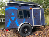Explore with this dark blue custom camper trailer, featuring a roof-top tent & unique topo-map graphics. Great for an RV rental!