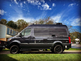 Dark grey Mercedes-Benz Sprinter-based camper van (Sanctuary RV) on a driveway under a blue sky, ideal for rv rental travel.