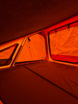 Cozy orange tent interior of an RV rental, featuring a comfortable sleeping area and mesh windows.