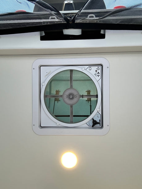 RV rental overhead view: MaxxAir ceiling vent fan with screen, an overhead light, and a black mesh privacy screen.
